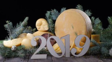 2019 rakamı ile ahşap tahta koymak lezzetli sert peynir çeşididir. Köknar ağacı dalları arkasında. Yeni yıl ve Noel kavramı. HD