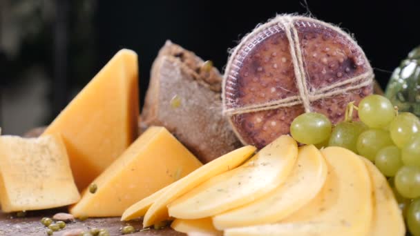 Concepto de catering. Variedad de queso duro bellamente colocado sobre fondo negro. Los cacahuetes se vierten desde arriba en cámara lenta. hd — Vídeo de stock