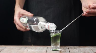 Barmen el dökme güçlü alkollü içecek içine bir atış bir şişe yavaş hareket dışında bir kaşıkla. Barmen alkollü kokteyl atış hazırlanıyor. HD