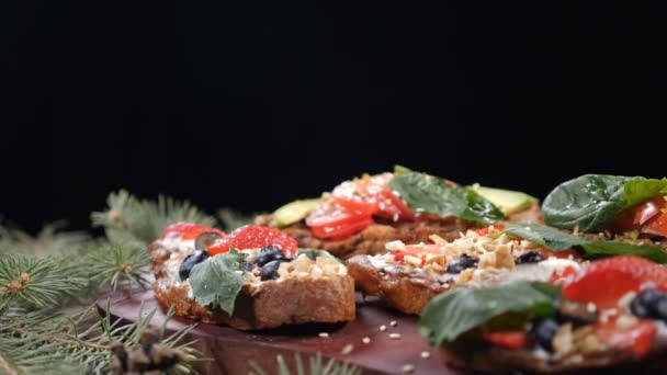 Sandwiches con mango, aceituna, lechuga y verduras frescas sobre fondo de madera. Pequeñas nueces cayendo en ramas de árbol de Navidad y plato con sándwiches vegetarianos. hd — Vídeos de Stock