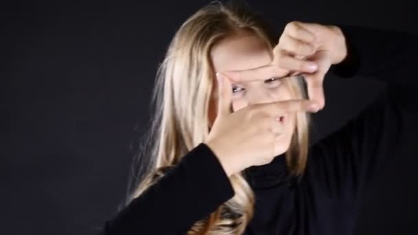 Portarait vicces kis tizenéves modell látszó-on fényképezőgép keresztül az ujjait. 4k — Stock videók
