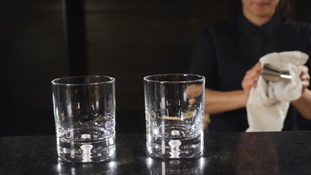 Conceito de bar. Barman feminino irreconhecível em camisa preta limpando jigger Cup pelo balcão de bar. Movimento lento. hd — Vídeo de Stock