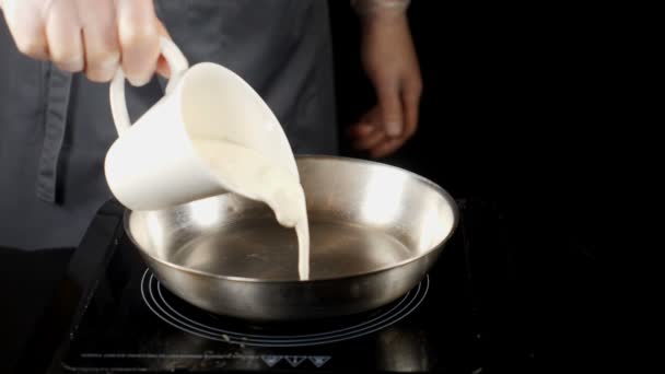 Professionisti al lavoro concetto. concetto di cucina raffinata. Chef in guanti versando panna in padella salsa di panna da cucina al rallentatore. hd — Video Stock