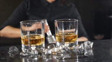 Gece hayatı bir kulüp. Kadın barmen buz küpleri ağır çekimde koyarak kadehlerin alkollü kokteyller hazırlanıyor. Buz ile su sıçramalarına düşme.