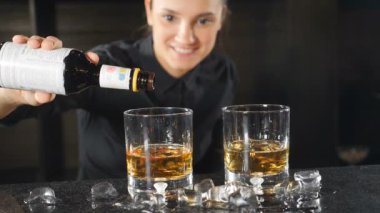 Barmen, alkollü kokteyl bar sayacı, bazı damla ağır çekimde ekleme yapıyor. Siyah tişörtlü içecek hazırlarken gülümseyen kadın barmen. HD