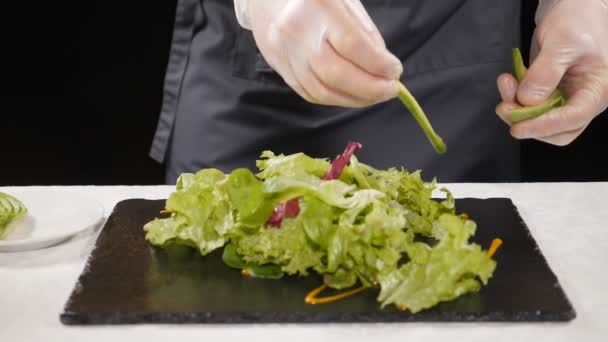 Vegetarisches Konzept. Gesunde Ernährung. Profi-Koch in Handschuhen, der Avocado-Scheiben auf Salat gibt und gesunden Salat zubereitet. Zeitlupe. hd — Stockvideo