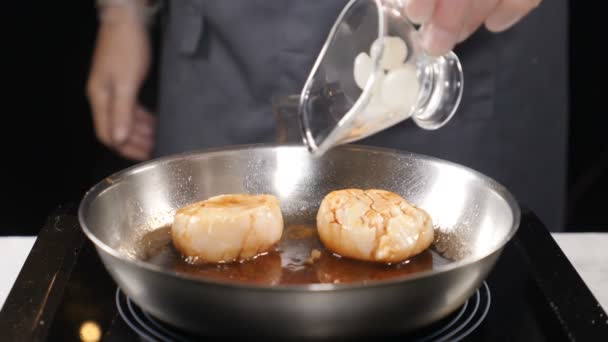 Cooking seafood. Healthy food and vegetarian concept. Professional chef in gloves adding small onion to scallops on frying pan. Slow motion. hd — Stock Video