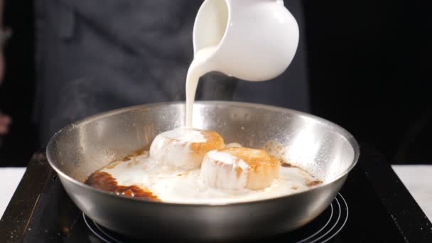 烹饪海鲜。健康食品理念。厨师在手套烹饪扇贝浇注奶油敷料在慢动作。高清 — 图库视频影像