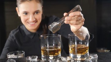 Gece hayatı bir kulüp. Kadın barmen buz küpleri ağır çekimde koyarak kadehlerin alkollü kokteyller hazırlanıyor. Buz ile su sıçramalarına düşme. HD