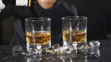 Kokteyl yapma kavramı. Barmen sayaç, alkol ile kokteyl bazı damla ağır çekimde eklemeyi kolaylaştırır. Siyah üniforma içecek hazırlarken gülümseyen içinde kadın barmen. HD