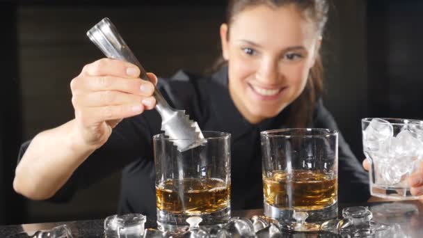 Życie nocne w klubie. Kobiece barman przygotowuje koktajle alkoholowe w kieliszki, kładzenie kostki lodu w zwolnionym tempie. Lód jest spada w dół z plamami. HD — Wideo stockowe