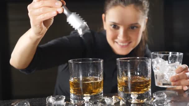 Cantinera arrojando cubitos de hielo en un vaso con whisky en cámara lenta. Hielo cayendo salpicando. Barman joven preparando cócteles alcohólicos. Hd — Vídeos de Stock