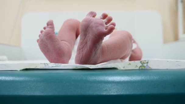 Νεογέννητο μωρό αγόρι βρίσκεται στην πλάτη. Το μωρό είναι κλοτσιές και απλώματος με τα δάχτυλά του sreading στα πόδια. Closeup γυρίστηκε σε μικροσκοπικά πέλματα νεογέννητο. Μωρό γλυκά στροφές του μεγάλο δάχτυλο του ποδιού και αγγίζει τα πόδια μαζί. 4k — Αρχείο Βίντεο