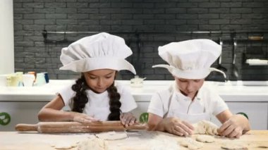 Chef şapka içinde şirin çocuklar kurabiye ve pasta özel evde yemek. Mutfak malzemesi arka planda. 4k