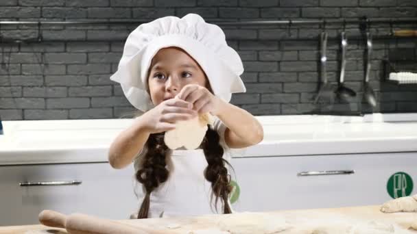 Bella ragazza adorabile in cappello da chef giocare con pasta e farina in cucina casa. Concetto di chef per bambini. I bambini giocano agli adulti. 4k — Video Stock