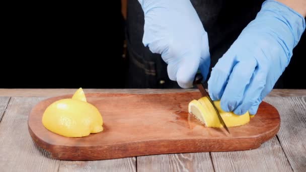 Chef en guantes rebanando limón sobre tabla de cortar de madera. Comida de restaurante arrullando. En cámara lenta. hd — Vídeos de Stock