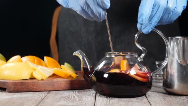 特写镜头的酒保用勺子在茶壶里搅拌水果。茶壶里有橘子、石灰、柠檬和苹果。慢动作。高清 — 图库视频影像