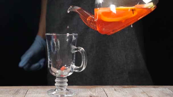 Primo piano colpo di tè alla frutta versando fuori dalla teiera trasparente in un bicchiere al rallentatore. hd — Video Stock