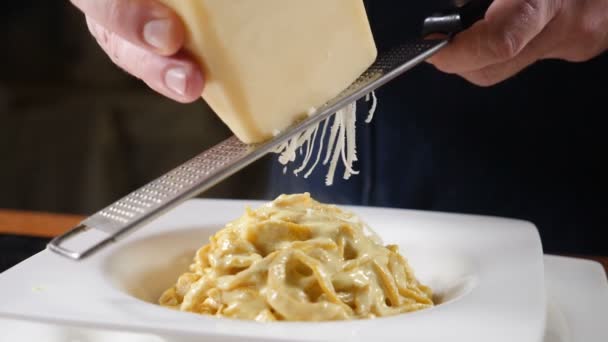 Restaurant eten koken. Chef-kok raspen van de kaas op stalen rasp voorbereiding van pasta met zeevruchten. Slow-motion. Concept van de mediterrane keuken. HD — Stockvideo