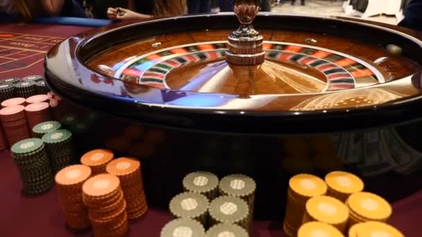 Närbild skott av casino roulette snurrande runt med kasinomarker lägga i högar nära. Händerna på urecognizable människor höll kort och marker, personer som spelande. Casino-konceptet. HD — Stockvideo