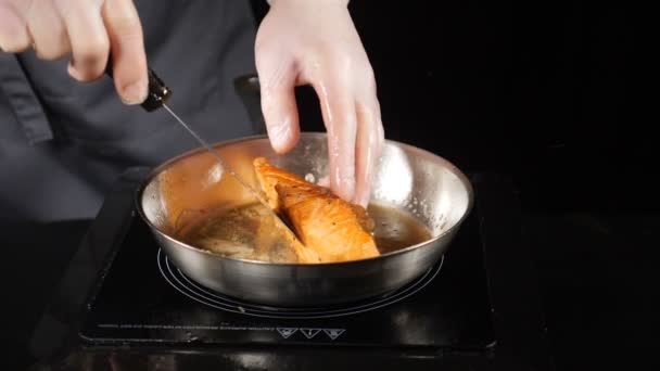 Ongezond voedsel concept. Gebakken zalm, forel. Zalmfilet huid zijde naar beneden op de pan. Plakjes rode vis gebakken in een pan. Chef-kok gieten olie met een lepel. HD. Slow motion. — Stockvideo