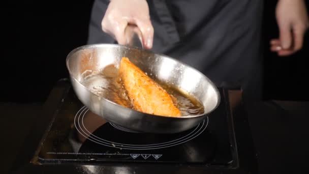 Concepto de comida grasa poco saludable. Salmón frito, trucha. Piel de filete de salmón boca abajo en la sartén. Trozos de pescado rojo fritos en una sartén. Chef vertiendo aceite con una cuchara. hd. Movimiento lento . — Vídeo de stock