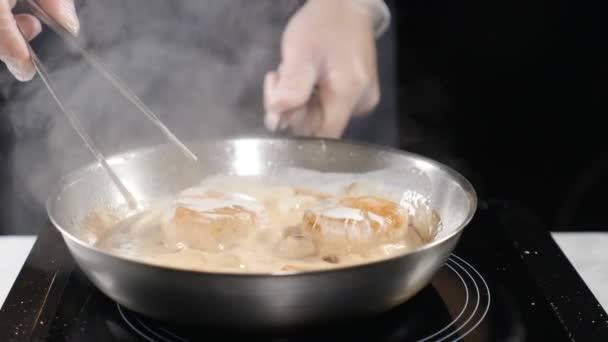 Cocinar mariscos. concepto de comida saludable. Chef profesional en guantes cocinando vieiras convirtiéndolas con alicates culinarios en cámara lenta. hd — Vídeo de stock