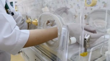 Yenidoğan annelik Kliniği kavram. Doktor el kuluçka cihazları veya couveuse bebek palm için parmak sensörler ayarlama kapatın. Bir bebek kuluçka makinesine bir gerçek bebek ya da erken çocuk sanki. Çocuk