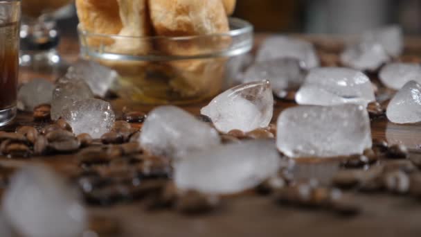 Concepto de cafetería. Cubos de hielo y granos de café sobre tabla de madera. Arte de la comida. Deliciosos croissants en tazón de cristal en el fondo. hd — Vídeos de Stock