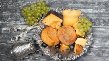 Lüks gıda kavramı. Peynir restoran hizmet. Gıda sanat kavramı. Sert peynir ve şube nadir Gümüş ahşap tahtaya plaka üzerinde üzüm çeşididir. Üstten görünüm vurdu. Ağır çekim. HD