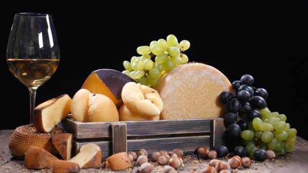 Σύνολο γύρο κεφάλι παρμεζάνα ή σκληρό τυρί parmigiano, σταφύλια σε ξύλινο κουτί και το κόκκινο κρασί. Πολλά καρύδια ή φουντούκι ρίχνονται σε αργή κίνηση. Πολυτελές εστιατόριο εικόνα. Dood τέχνη. Τυρί εραστές. HD — Αρχείο Βίντεο