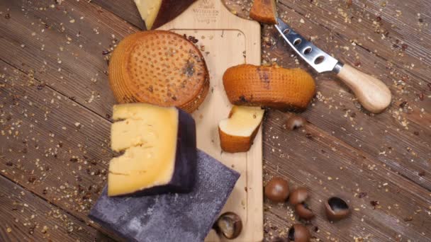 Vídeo de comida. Vista superior plano en la vatiedad de queso duro delicioso colocado en la tabla de cortar de madera. Restaurante concepto de comida de lujo. Las nueces se lanzan en cámara lenta añadiendo actividad. hd — Vídeo de stock