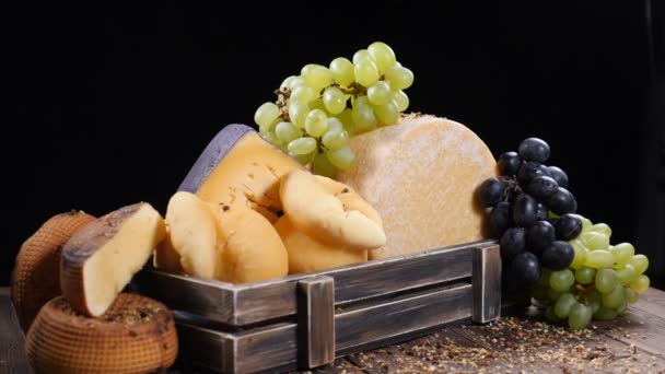 Set de queso duro bellamente puesto en caja de madera decorada con uvas. Especias que caen sobre la composición en cámara lenta. Sala de exposición del restaurante. Arte de la comida. hd — Vídeos de Stock