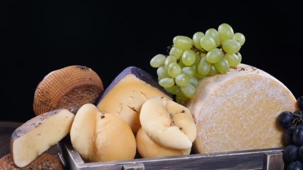 Set de queso duro bellamente puesto en caja de madera decorada con uvas. Especias que caen sobre la composición en cámara lenta. Sala de exposición del restaurante. Arte de la comida. hd — Vídeo de stock
