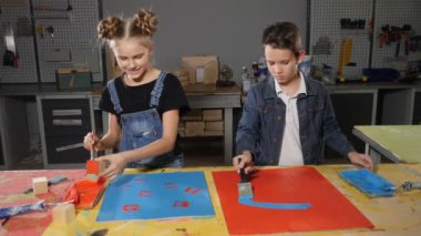 Çocuk fırça ile boya. El sanatları Atölyesi. Okul çağındaki çocuklar birlikte resim ve having fun çalışma. Silindirler üzerinde pait.
