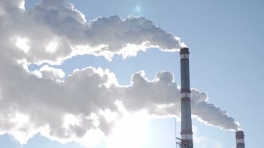 Küresel ısınma sorunu. Beyaz duman termik stationboiler Oda, termik santral, mavi gökyüzü, bulutlar duman ve arkasında güneş karşı beyaz duman baca dan. çok soğuk. 4k