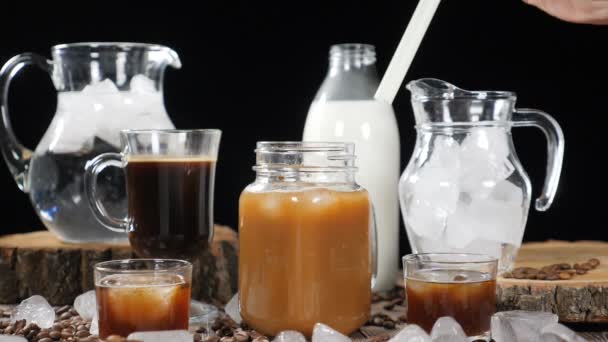 Videoimage sada lahví a sklenic s mlékem, voda, černá káva a karamelový nápoj. Ženská ruka uvedení slámy do sklenice v pomalém pohybu. HD — Stock video