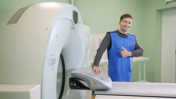 计算机断层扫描概念。ct mri 扫描仪附近的年轻男性患者。大拇指向上。健康理念。磁共振检查。高清 — 图库视频影像
