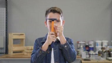 Çocuk ve bina çekiçle uygular ve kapatma ve gülümseyerek gözlerini açarak elinde çivi. El sanatları kavramı. Çilingirler atölye hobi ve boş zaman zaman. 4k