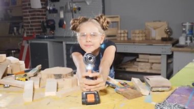 Kameraya poz ahşap marangozluk elektronik bir matkap tutan komik 10 yaşındaki kız portresi. Küçük Oluşturucusu kavramı. HD