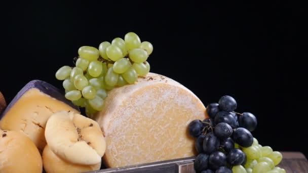 Ensemble de fromage à pâte dure joliment mis dans une boîte en bois décorée de raisins. Épices tombant sur la composition au ralenti. Salle d'exposition du restaurant. Art culinaire. hd — Video