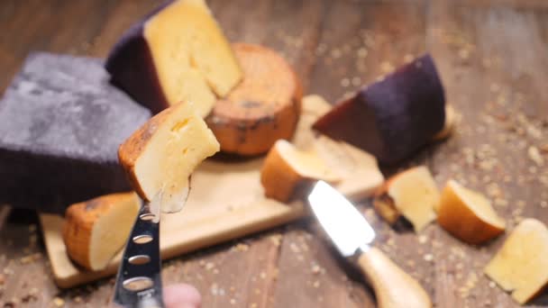 食品ビデオ。ハードおいしいチーズの vatiety で撮影上面は木製のまな板に配置されます。レストランの高級食品のコンセプト。チーズの美味しい部分を持つチーズ ナイフ。hd — ストック動画