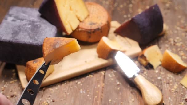 食品ビデオ。ハードおいしいチーズの vatiety で撮影上面は木製のまな板に配置されます。レストランの高級食品のコンセプト。チーズの美味しい部分を持つチーズ ナイフ。hd — ストック動画