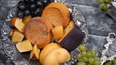 Lüks gıda kavramı. Peynir restoran hizmet. Gıda sanat kavramı. Sert peynir ve şube nadir gümüş tabak ve ahşap tahtaya diğer gereçler üzerinde üzüm çeşididir. Üstten görünüm vurdu. Ağır çekim