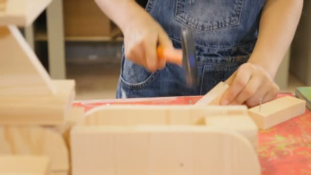 Barnen leker på craft workshop. Närbild bild av en flicka hamring naglarna. Bedårande flicka i jeans. 4k — Stockvideo