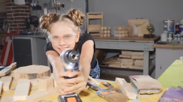 Portrét legrační 10 let staré dívky v dřevěné tesařské drží elektronická vrtačka, Pózování na kameru. Malý tvůrce koncepce. HD