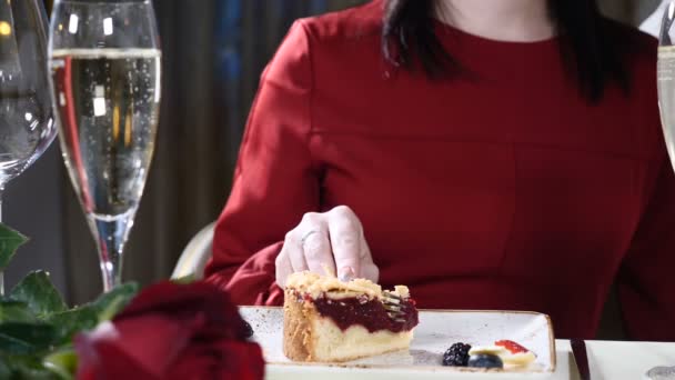 Unrecognizable attractive brunette eating a piece of cake with a fork in a cafe. Two glasses of champagne on table. Romantic concept. hd — Stock Video