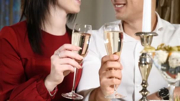 情侣们在餐馆里碰杯。特写。在餐厅喝浪漫晚餐的年轻男女, 庆祝2月14日。浪漫的概念和爱情。高清 — 图库视频影像