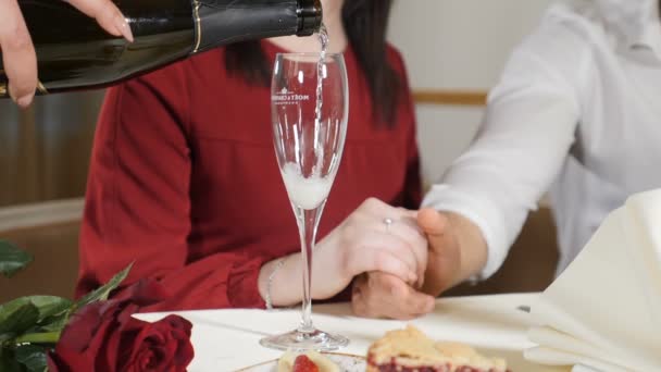 Middellange schot van jonge paar handen op tafel. Slow Motion van Ober gieten Champagne aan liefdevolle paar gelet romantisch diner in restaurant. Romantische concept. HD — Stockvideo