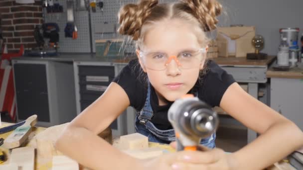 10-jarige meisje en een boor in handen. Slow-motion. Mooi meisje builder is bedrijf boor in haar handen, inschakelen, glimlachen, gebouw conceptie. HD — Stockvideo